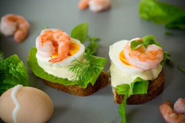 Sandwich with egg and shrimp on gray background from above
