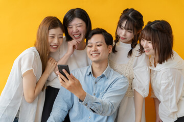 スマホ画面を囲んで楽しむ若者グループの笑顔の瞬間