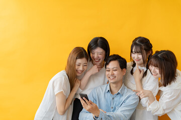 スマホ画面を囲んで楽しむ若者グループの笑顔の瞬間