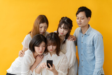 Fototapeta premium スマホ画面を囲んで楽しむ若者グループの笑顔の瞬間
