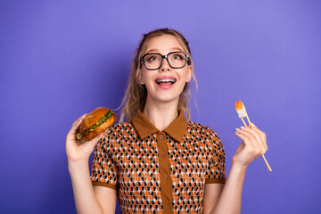 Cute young girl with burger and sushi smiles against purple background in a fun casual lifestyle moment