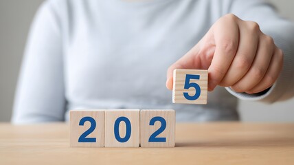 2025 new year concept with hand placing wooden number block on table