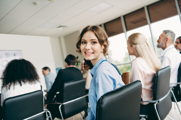 Obraz premium Young professional woman attending a business conference, engaging with coworkers and colleagues in a modern office setting