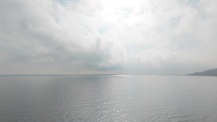 Aerial drone view of calm sea under thick fog, showing soft horizon, minimalistic seascape, muted colors and atmospheric weather conditions from above. - Powered by Adobe