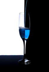 Champagne glass with blue liquid on black and white background