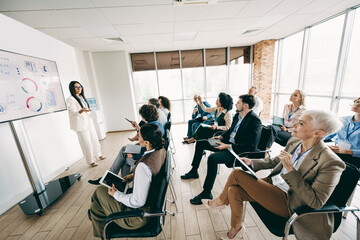 Professional team meeting in modern office with diverse coworkers attending a presentation and collaborating effectively