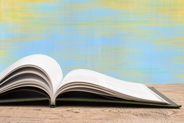 Composition with hardback books, fanned pages on wooden deck table and blue background. Books stacking. Back to school. Copy Space. Education background.