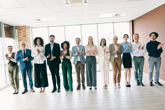Group of diverse professionals celebrating teamwork in a modern office setting, showcasing collaboration, unity