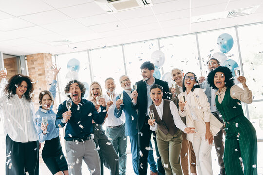 Group of businesspeople celebrating success in the office with confetti and champagne, representing teamwork