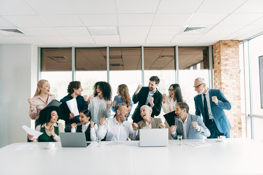 Business team celebrating collaborative success with enthusiasm in a modern office setting, promoting teamwork and motivation