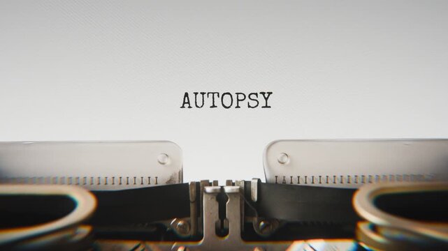 Old mechanical typewriter typing Autopsy in a close-up view, with metal letters striking the white paper.