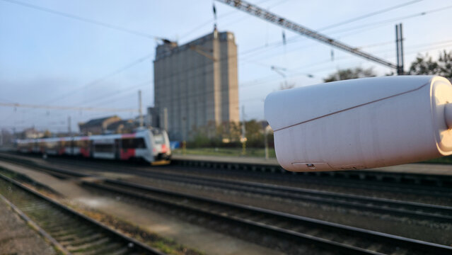 Surveillance camera overlooking railway tracks with a moving train in soft focus, capturing themes of monitoring, transit, security, and modern connected infrastructure.