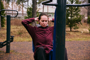 Obraz premium A young woman exercises on outdoor equipment at a sports ground