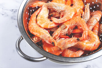 freshly frozen shrimp in a metal colander, for cooking, top view, close-up, on a marble table, no people,