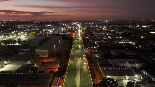 Aerial view of city lights illuminating the dark sky while cars speed along the highway, creating streaks of light, Regency Park, South Australia, Australia.