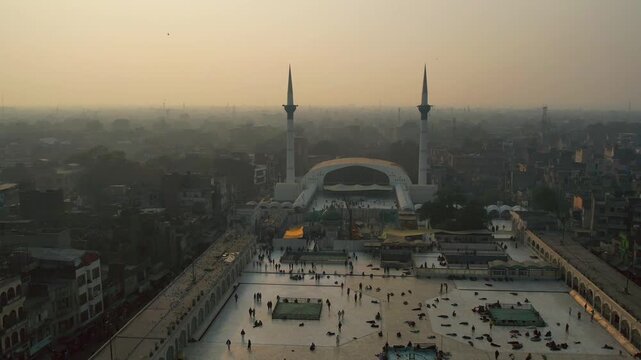Lahore, Pakistan - 29 July 2025: Aerial view of the Data Darbar Mosque, its white facade standing out against the sprawling city below, bathed in the soft light of dawn.