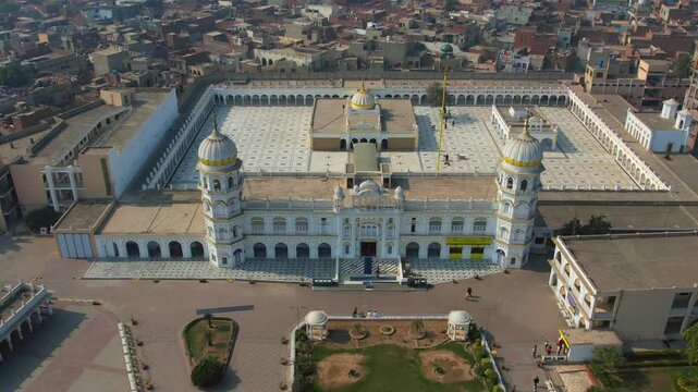 Aerial view of Gurdwara Janam Asthan with its white facade, domes, and courtyard, contrasting with the surrounding buildings, Nankana Sahib, Punjab, Pakistan.