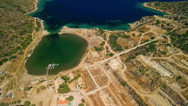 Aerial view of the ancient Knidos ruins and a serene harbor with turquoise waters, contrasted by the arid landscape, Knidos, Mugla, Turkey.