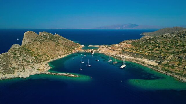 Aerial view of azure waters filled with boats, contrasting with the arid landscape of Knidos, creating a scene of serene beauty, Knidos, Mugla, Turkiye.