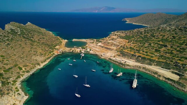 Aerial view of the serene turquoise waters meeting the rugged coastline near the ancient city of Knidos, with boats dotting the harbor, Knidos, Mugla, Turkiye.