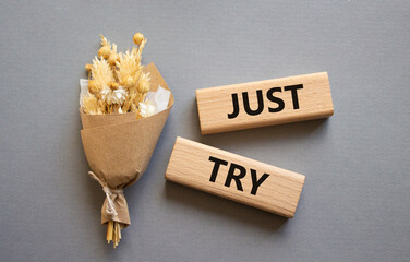 Just try symbol. Concept words Just try on wooden blocks. Beautiful grey background with bouquet of flowers. Business and Just Try concept. Copy space.