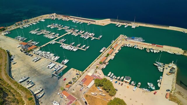 Aerial view of Kormen Marina's turquoise waters dotted with yachts, contrasting with the deep blue sea and the coastline, Datca, Mugla, Turkiye.