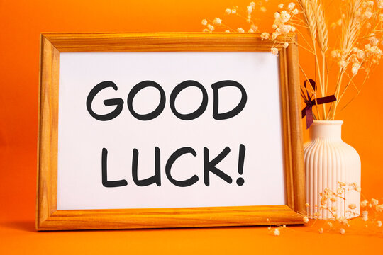 Good luck symbol. Concept words Good luck on beautiful wooden picture frame. Beautiful orange background with flower vase. Business and Good luck concept. Copy space. - Powered by Adobe