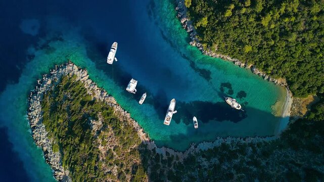 Aerial view of boats floating on the turquoise waters of Mersincik bay, contrasting with the deep blue sea and lush green coastline, Datca, Mugla, Turkiye.