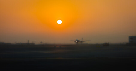 A plane landing at Dubai Airport, United Arab Emirates, at sunrise.