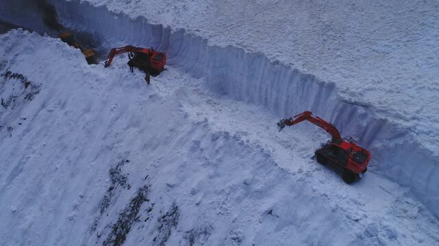 Aerial view of excavators bravely cutting through the thick snow at Babusar Pass, creating a pathway through the icy landscape, Babusar, Khyber Pakhtonkhawa, Pakistan.
