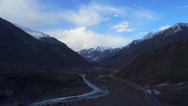 Aerial view of snow capped mountains and river flowing alongside a road, offering picturesque scenery, Naran, Khyber Pakhtunkhwa, Pakistan.