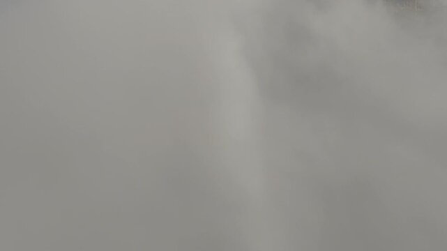 Aerial view of rolling clouds caressing the mountainous landscape with a faint rainbow in the distance, dolomiti, Veneto, Italy.