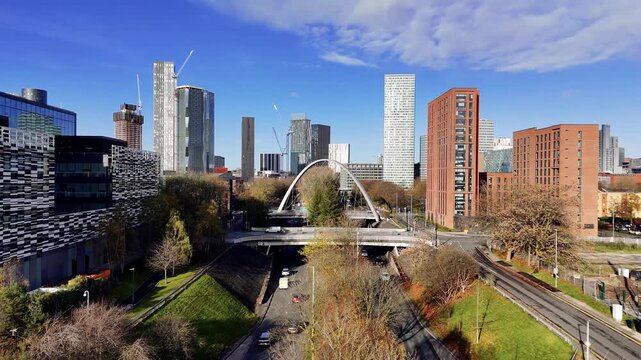 Drone video footage of the Manchester skyline - rising drone shot of the Manchester city center skyscrapers and the famous Hulme Arch Bridge - blue sky and sunny weather