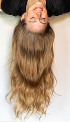 A woman with long blonde hair is upside down on white