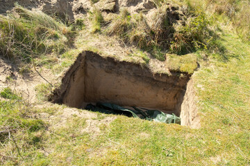 Neat rectangular hole in the ground in the sand dunes, at Formby, Merseyside, England,UK. It's not a grave but it looks very like one.