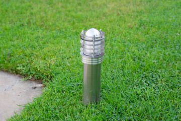 Side view of a small modern metal silver, outdoor garden light on a lawn