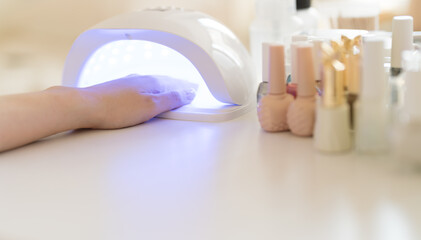Hands with nail polish cured in a UV nail lamp