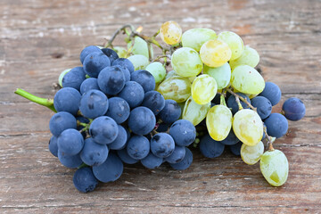 Clusters of purple and white grapes on rustic wooden table