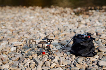 outdoor gear setup, arranging camping and cooking equipment, positioning outdoor cooking tools during brief hike break, organizing camping utensils and portable stove for quick outdoor meal stop