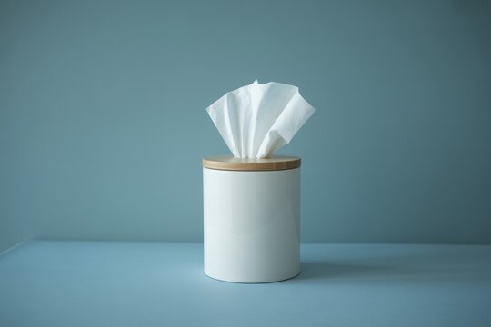 Tissue box on blue table in bright room with clean handkerchief