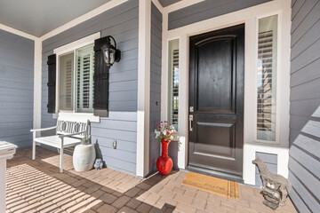 The charming porch features a striking black door and a white bench
