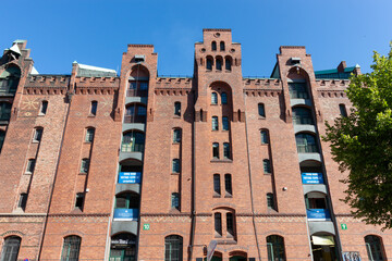 The impressive red brick facade of a traditional warehouse in Hamburg's Speicherstadt, housing Miniatur Wunderland and a Digital Hub, under a bright blue sky