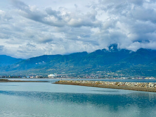 Palu city waterfront view beneath dramatic clouds with mountains and mosque in the distance creating peaceful scenery