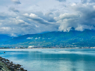 Palu city coastal view nestled beneath majestic mountains and dramatic cloudy skies offers peaceful travel inspiration