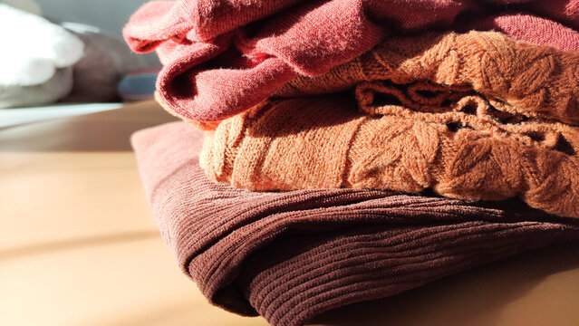 A stack of soft wool sweaters glows in natural light. The image evokes autumn comfort and gentle homey atmosphere.