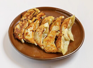 Fried gyoza dumplings, pan fried to perfection, on a rustic plate. Ideal for showcasing authentic Asian cuisine and culinary delights.