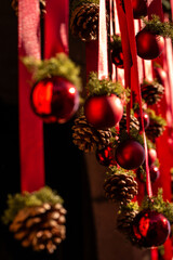 A festive Christmas decoration with red ribbons, pinecones, and shiny ornaments, warmly lit by sunlight to create a natural and cozy holiday atmosphere.