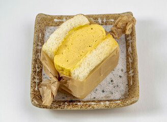 Delicious tamago egg sandwich. Perfect for a quick lunch, snack, or savory breakfast. Enjoy this tasty egg filled treat on a rustic plate.
