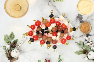 Christmas and New Year's dishes, a set of snacks and refreshing drinks for the festive table. A plate with canapes of tomatoes, mozzarella cheese, olives, black olives and grapes on a marble table