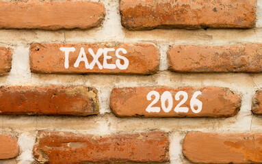 Taxes 2026 new year symbol. Concept words Taxes 2026 on beautiful brown brick wall. Beautiful brown brick wall background. Business and taxes 2026 new year concept. Copy space.